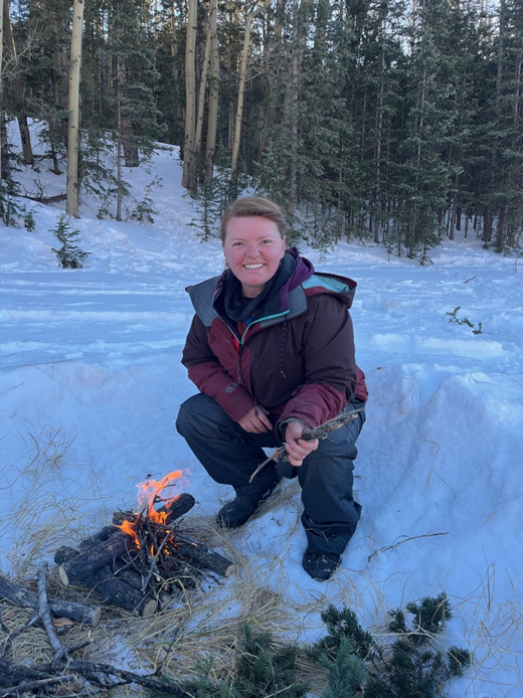 A good warming layer is all about releasing moisture and insulating heat. This means it will hold heat in, but it will also hold heat out. This student will be warmer if she opens her coat to allow heat from the fire in.