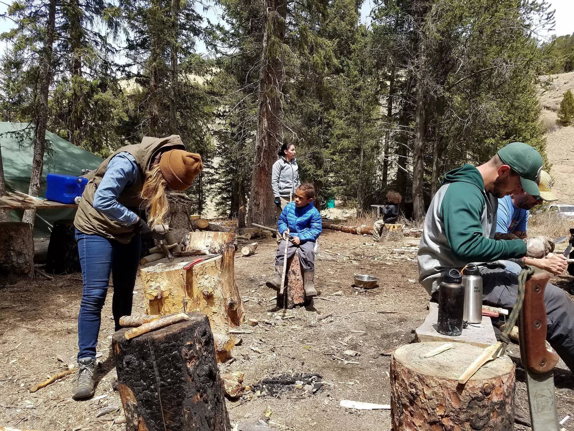 Participants practice fire building in the forest during a beginner survival course.