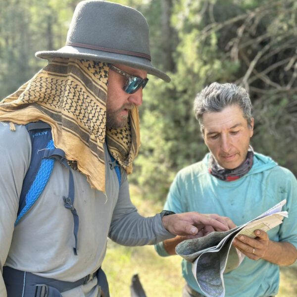 Two people studying a topographic map in the forest during a navigation course.