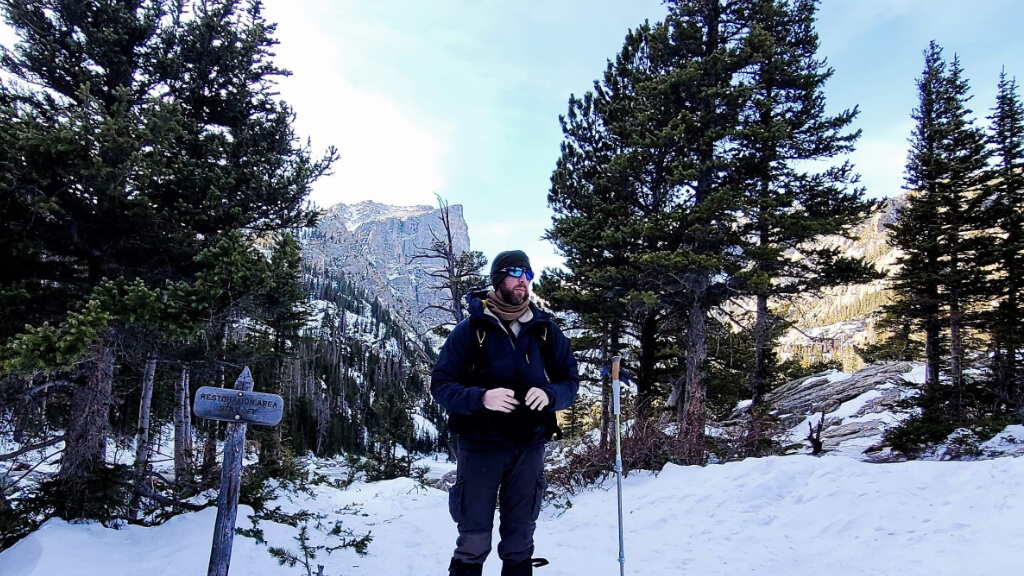 Jason Marsteiner walking through snowy forest in cold conditions that appear manageable but can quietly lead to hypothermia