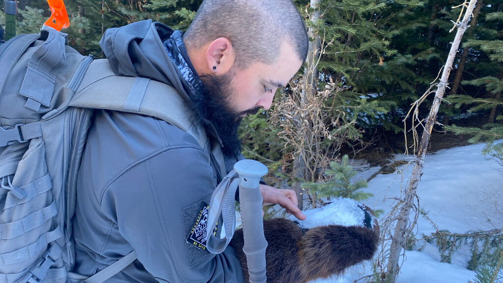 Winter survival instructor focused on a small task in snowy forest, illustrating tunnel vision and impaired judgment caused by hypothermia.