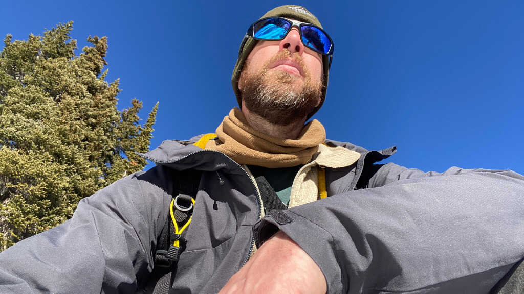 Jason Marsteiner seated in a winter mountain environment, pausing to assess conditions during cold weather training