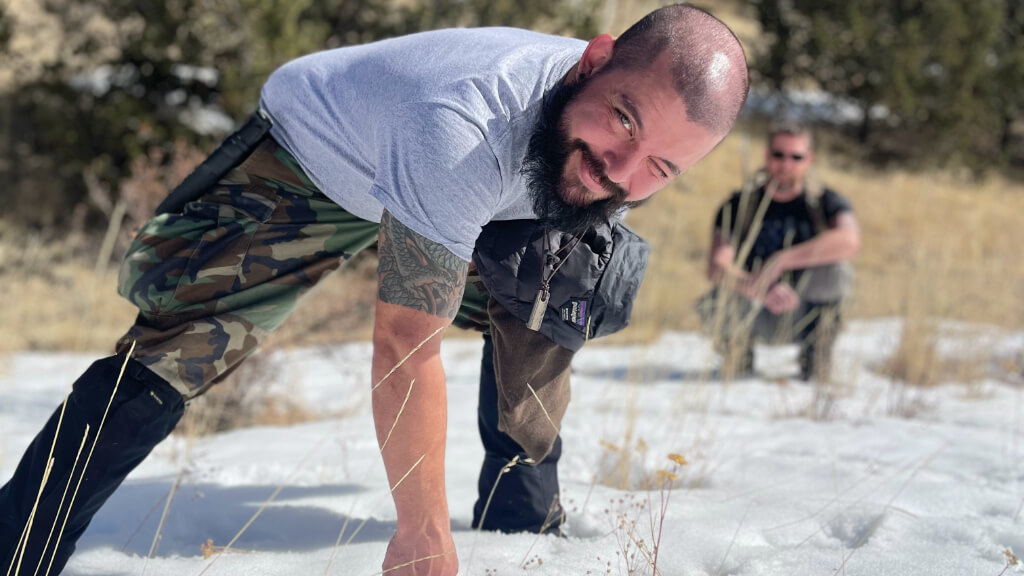 Instructor standing in snow wearing a T shirt during cold weather training, illustrating paradoxical undressing caused by hypothermia related judgment failure