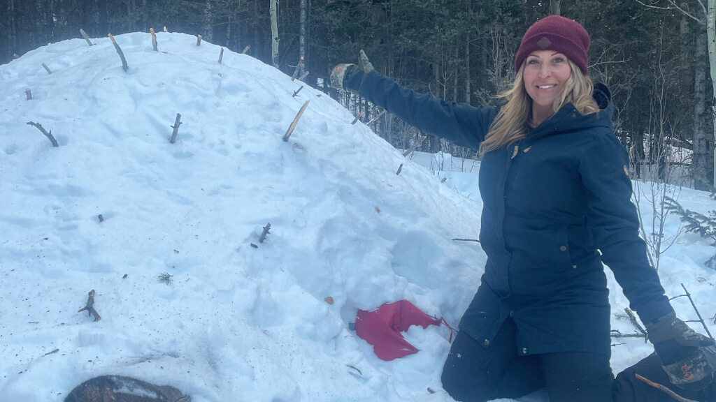 Jess Caldwell building a snow shelter during winter survival training, demonstrating real world hypothermia prevention and decision making