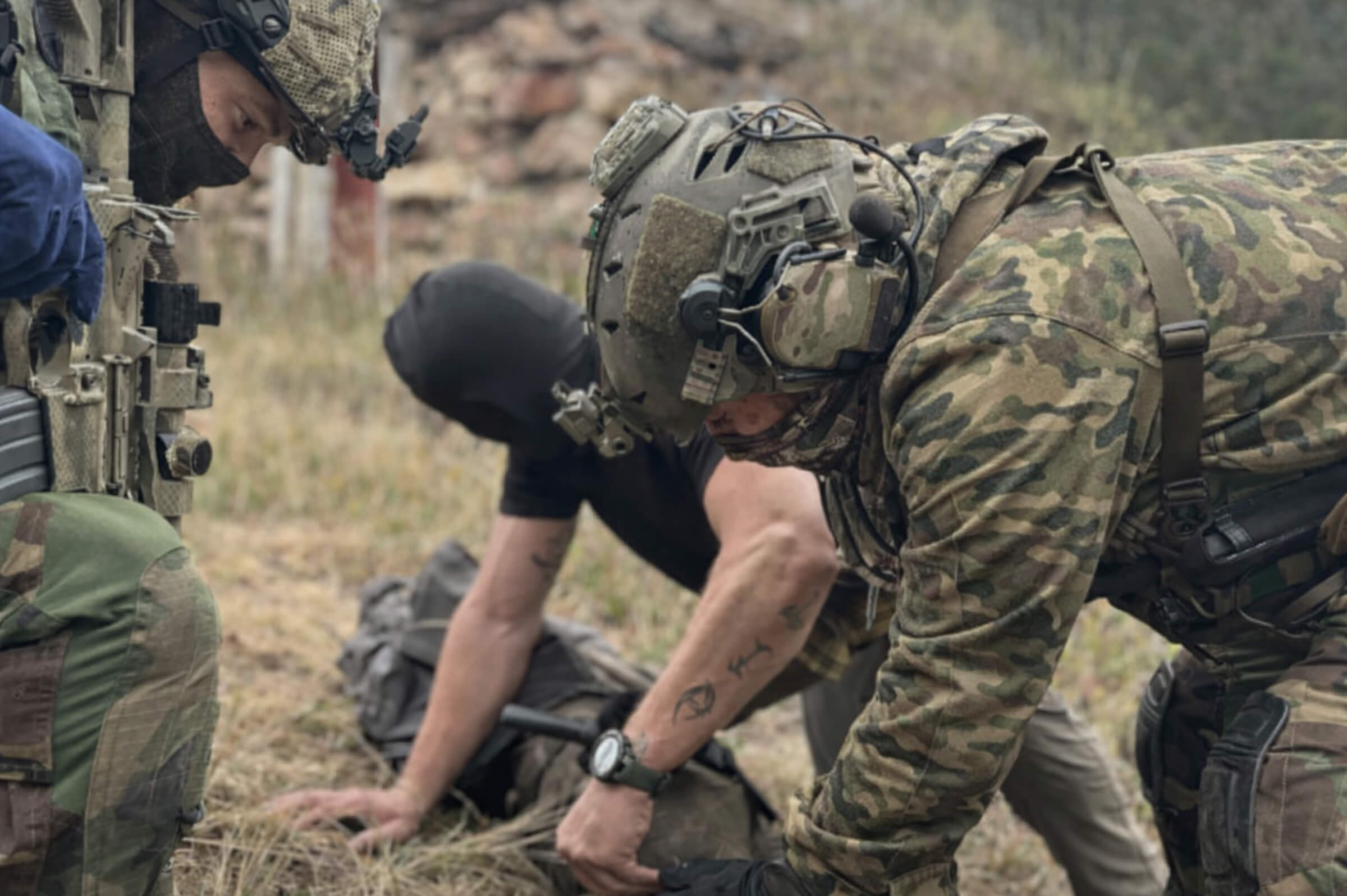 Instructors conducting hands on resistance training during a SERE based tactical scenario