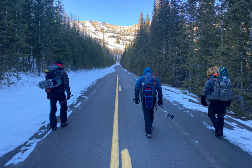 Group of hikers walking together down a snow lined mountain road after turning around from an objective