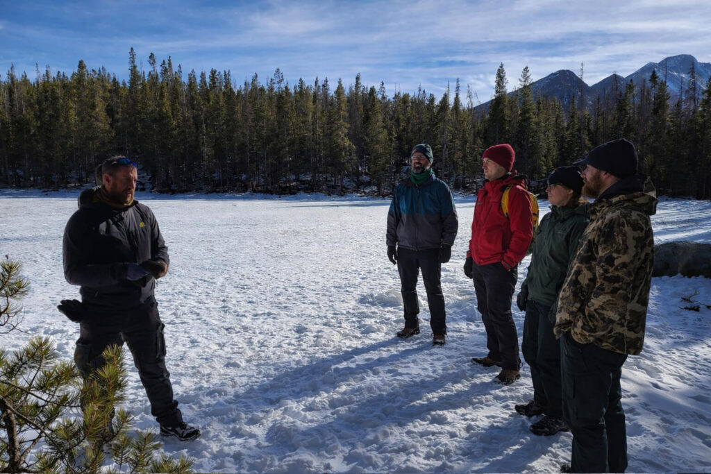 Outdoor group standing in a half circle during winter pre trip planning discussion before a mountain hike