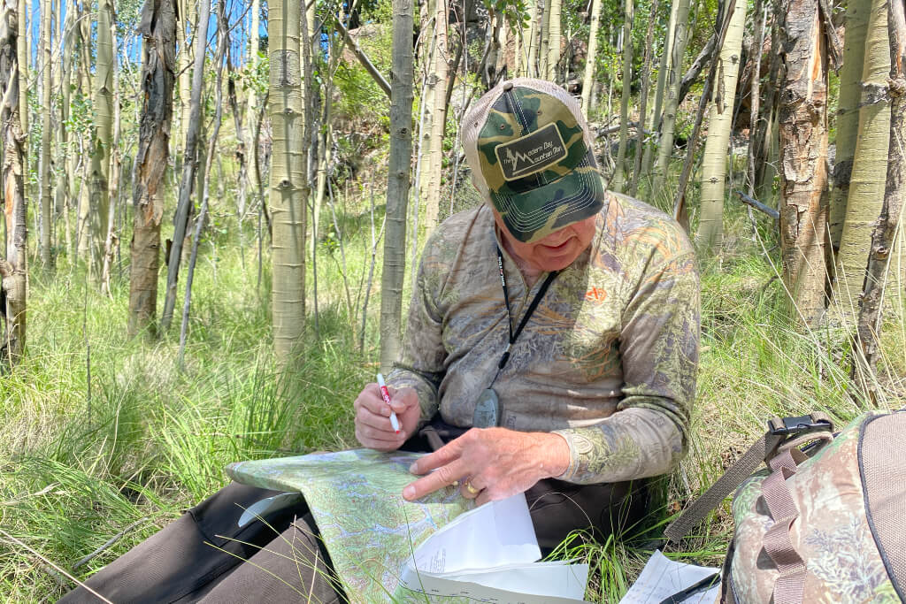 Hiker sitting in the forest studying a topographic map to determine location and direction