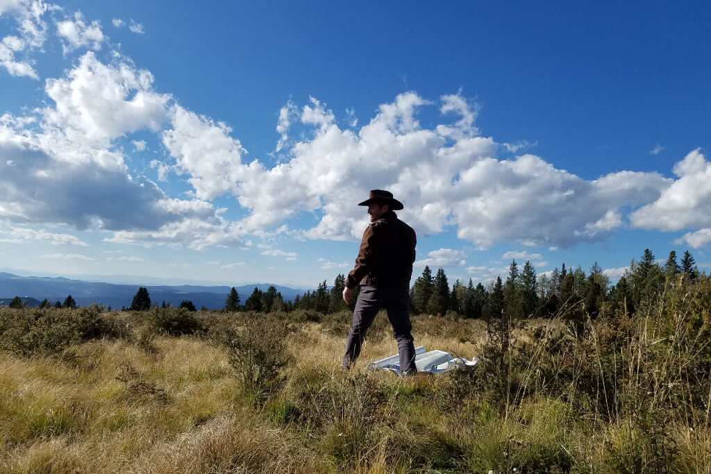 Hiker standing in open mountain terrain scanning the landscape after losing the trail