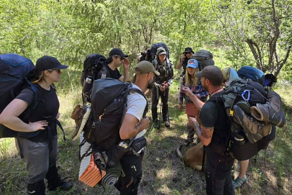 Instructor leading group of students during wilderness survival leadership training hike in Colorado forest