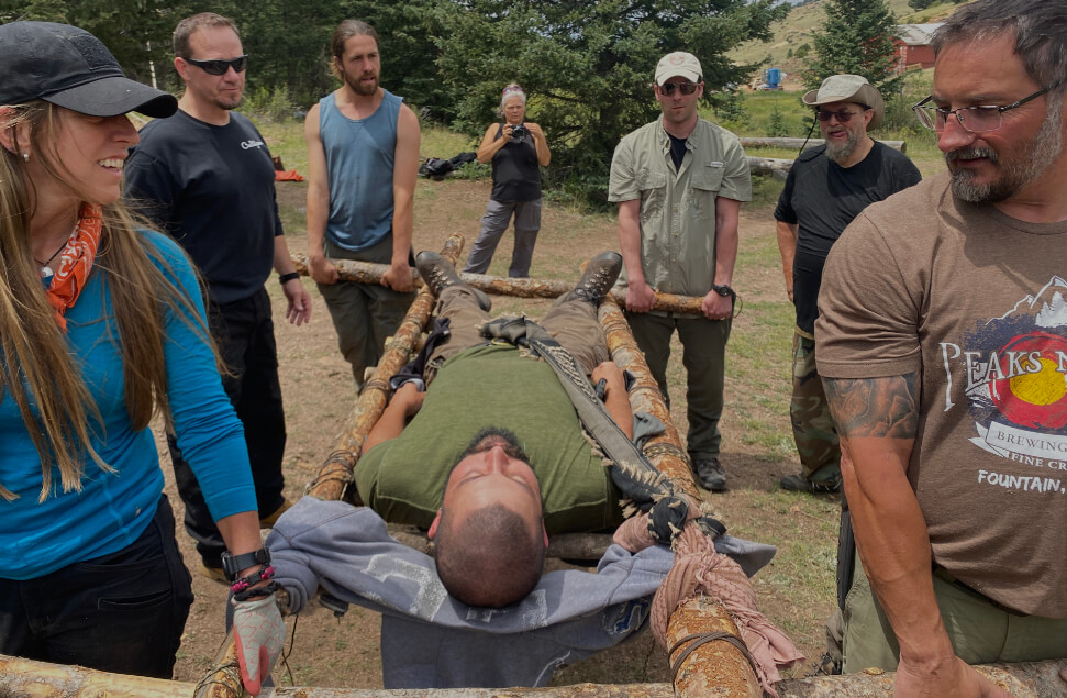 Team carrying a person on a handmade stretcher during hands-on leadership training in the Colorado backcountry