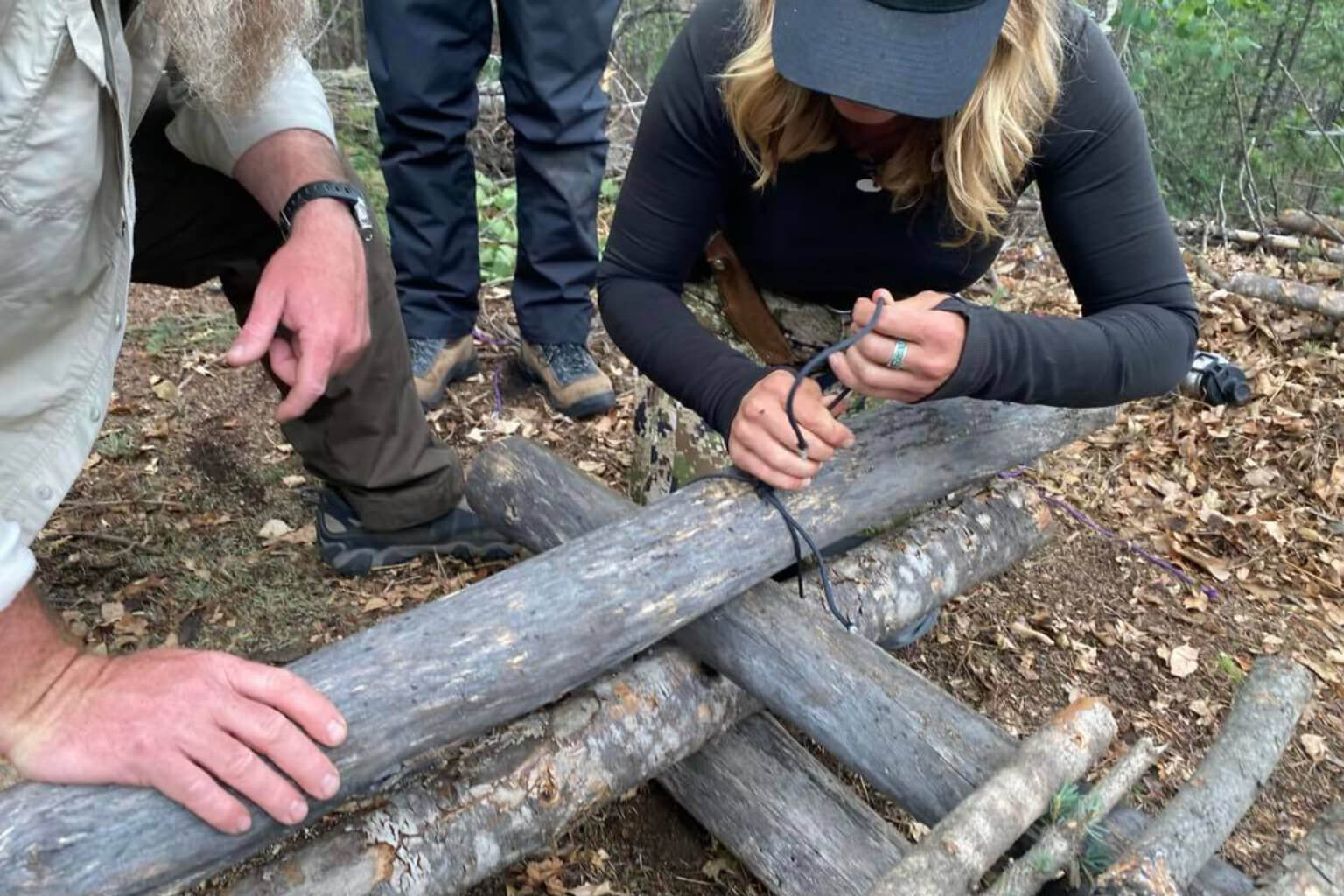 A student practices lashing wood with cordage during shelter construction