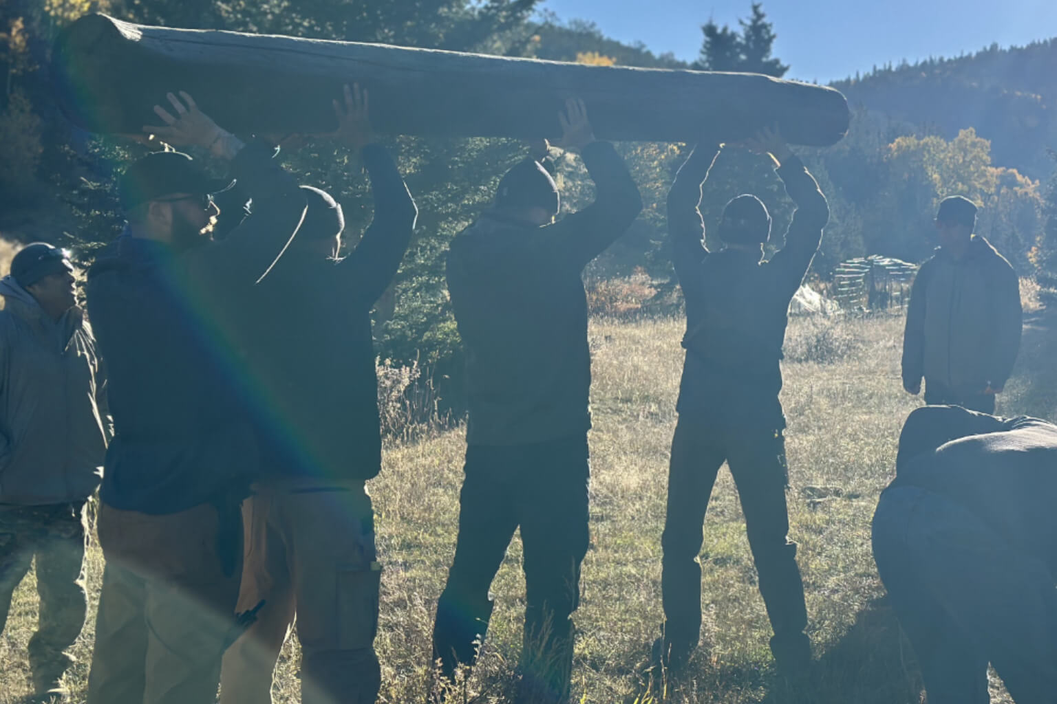Team carrying a large log together during outdoor leadership and survival training in Colorado