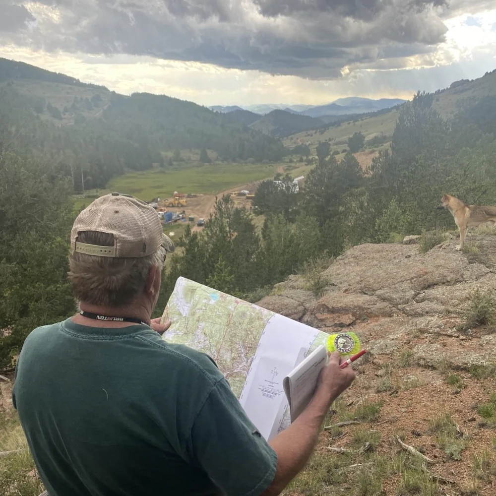 Navigation student holding a topographic map and compass while studying the surrounding terrain.